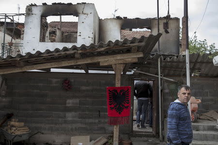 A man looks on next to a destroyed house decorated with an Albanian flag in Kumanovo, Macedonia, May 11, 2015. REUTERS/Marko Djurica