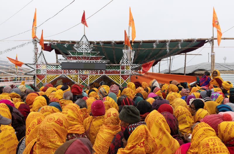 Hindu devotees wait to collect free blankets at the tent city built for the pilgrims on the banks of the Sarayu river ahead of the opening of the temple of Lord Ram in Ayodhya