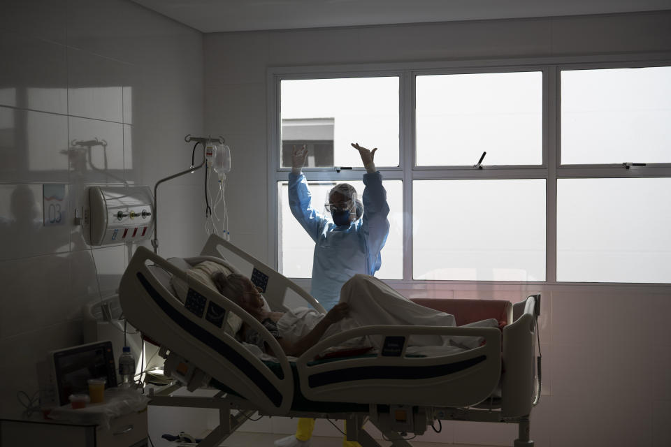 A nurse talks to a COVID-19 patient at the Dr. Ernesto Che Guevara hospital, that exclusively treats new coronavirus cases, in Marica, Brazil, Thursday, May 21, 2020. (AP Photo/Leo Correa)