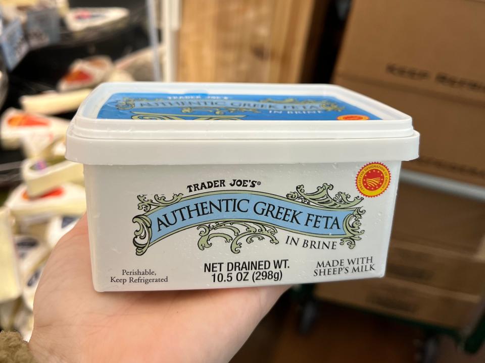 The writer holds a container of Trader Joe's authentic Greek feta