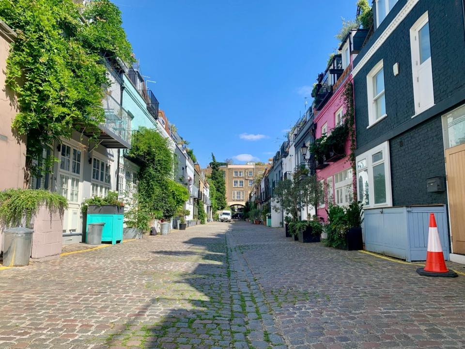 A straight shot of St. Lukes Mews with the famous pink house from Love Actually on the right and other colorful homes beside it.