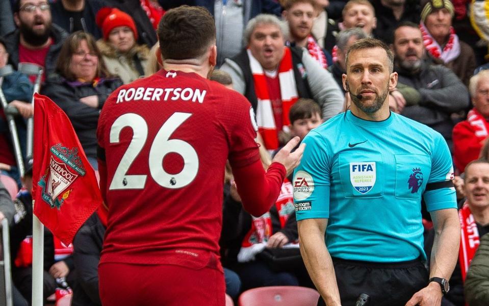 Liverpool's Andy Robertson and the assistant referee Constantine Hatzidakis - Shutterstock/Peter Powell