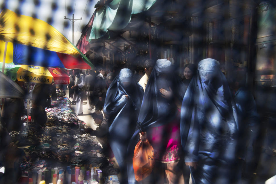 FILE - Seen through the eye grid of a burqa, women walk through a market in Kabul, Afghanistan on Thursday, April 11, 2013. (AP Photo/Anja Niedringhaus, File)