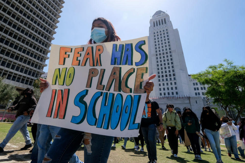 a person holding up a sign that says, fear has no place in school