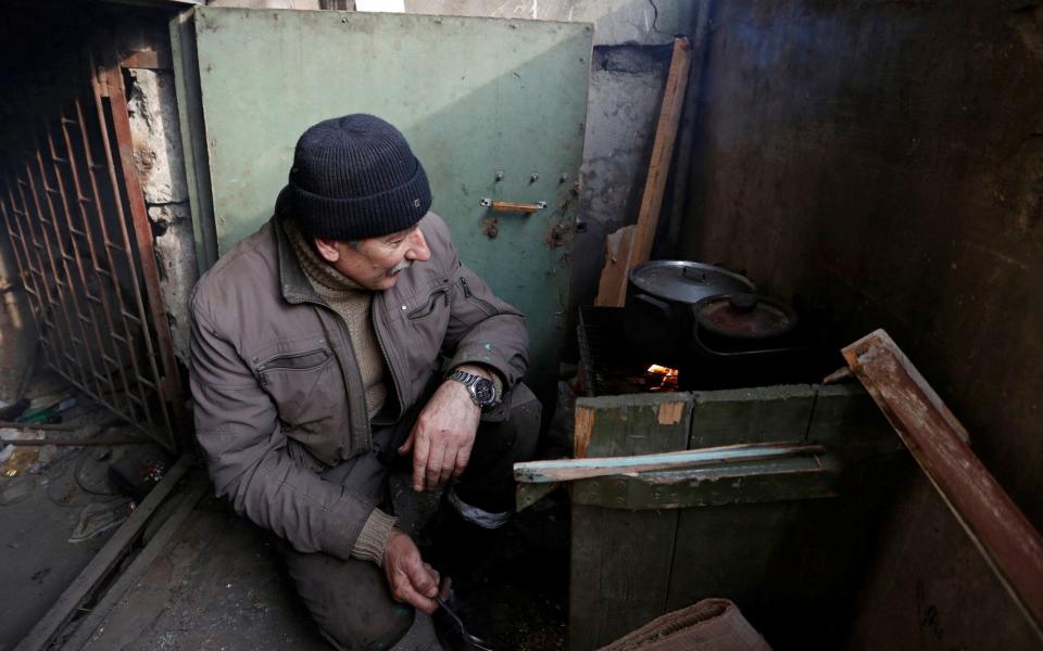 Metallurgist Viktor, 63, cooks food at the entrance to the basement of an apartment building in Mariupol - REUTERS/Alexander Ermochenko