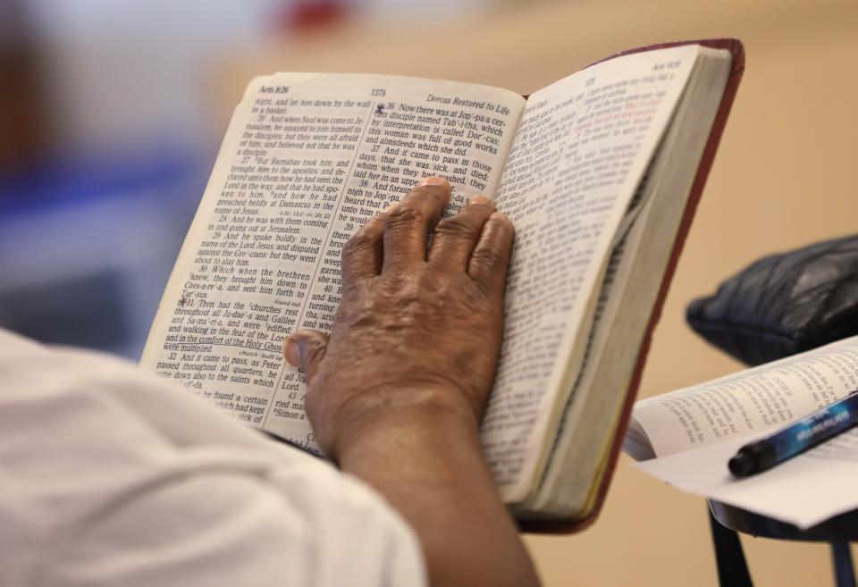 Members of the Fairy Grandparents follow along in a Bible during a reading from John Chapter 9 at the Lewis Street YMCA Neighborhood Center.