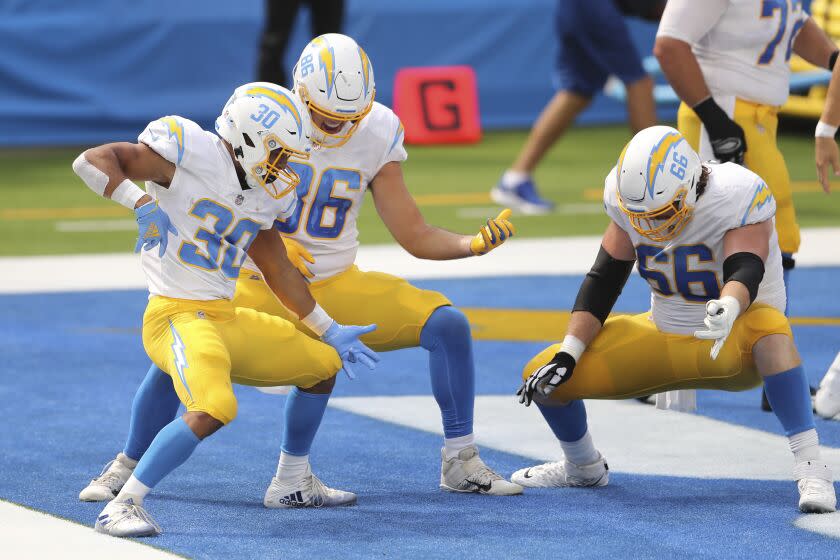 Los Angeles Chargers running back Austin Ekeler (30) follows his touchdown with an ai guitar celebration with Los Angeles Chargers tight end Hunter Henry (86) and Los Angeles Chargers center Dan Feeney (66) during an NFL football game against the Carolina Panthers, Sunday , Sept.  27, 2020, in Inglewood, Calif.  (AP Photo/Peter Joneleit)