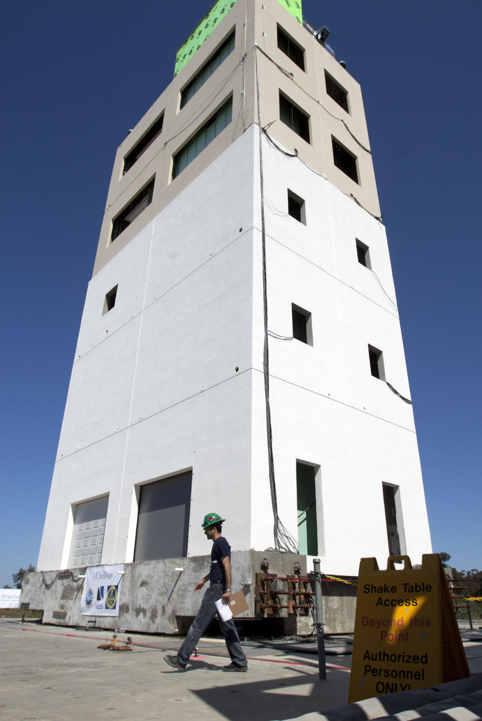 A researcher walks in front of a five-story building constructed to study earthquakes at a facility run by the University of California at San Diego Tuesday, April 17, 2012, in San Diego. To study the affects of earthquakes, researchers will repeatedly shake a building over a span of two weeks as part of the $5 million experiment funded by government agencies, foundations and others. (AP Photo/Gregory Bull)