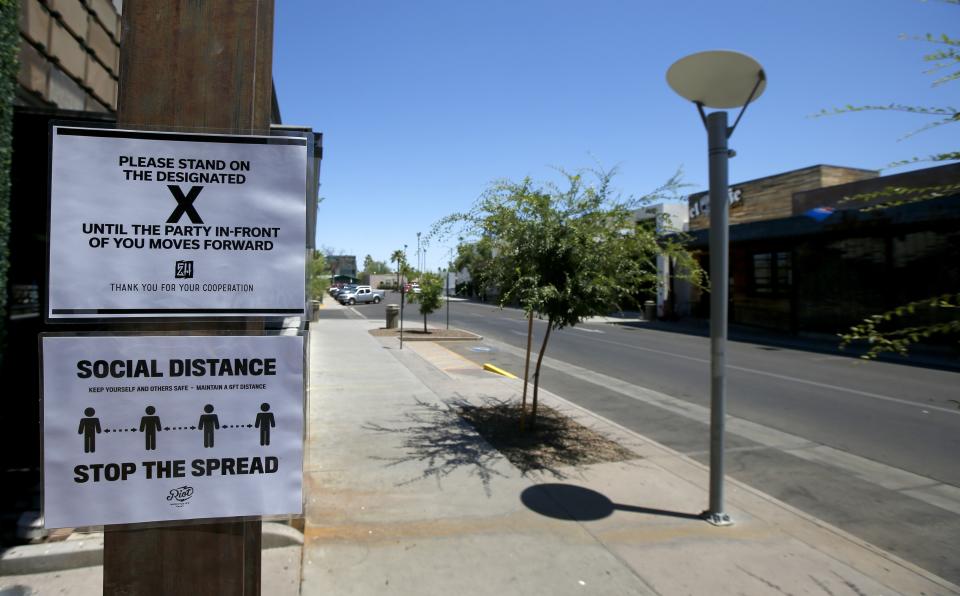 Social distancing signs are posted at one of the bars closed for the next 30 days due to the surge in coronavirus cases Tuesday, June 30, 2020, in Scottsdale, Ariz. (AP Photo/Ross D. Franklin)