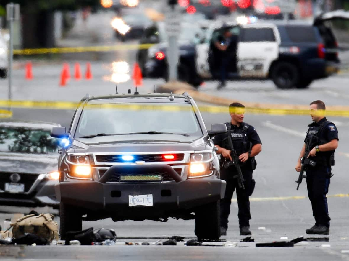 Police officers gather after two armed men entering a bank were killed in a shootout with police in Saanich, B.C., on June 28, 2022.  (Kevin Light/Reuters - image credit)