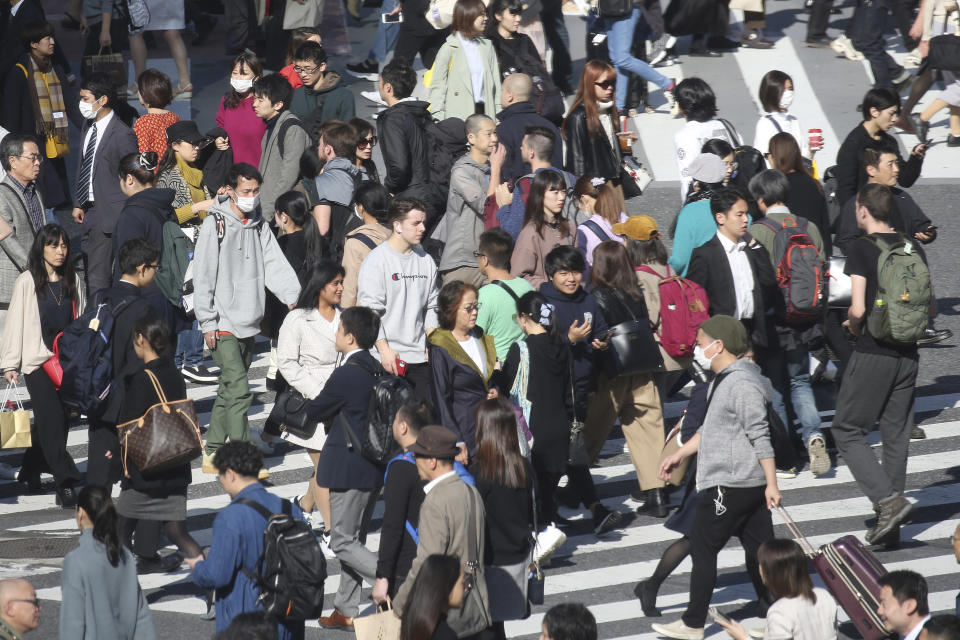 In this Nov. 14, 2019, photo, people cross a street in Tokyo. A closely watched economic survey by the Bank of Japan showed sentiments among major manufacturers soured for the fourth straight quarter, the “tankan” survey released Friday, Dec. 13, 2019. A trade war between the U.S. and China crimped trade and growth. Japan’s growth is dependent on exports and any slowdown in pan-Pacific trade hurts company sentiments. (AP Photo/Koji Sasahara)