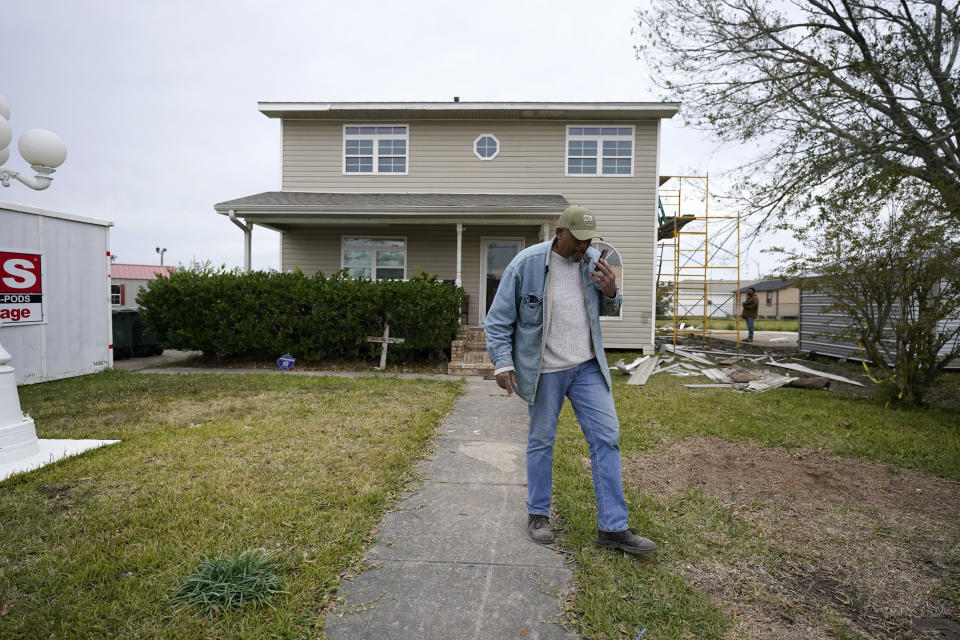 CORRECTS FIRST NAME TO WILFRED - Wilfred Trahan talks on his phone while workers repair siding on his damaged home, in the aftermath of both Hurricane Laura and Hurricane Delta, in Lake Charles, La., Friday, Dec. 4, 2020. (AP Photo/Gerald Herbert)