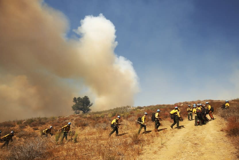GAVIOTA COAST, CA - OCTOBER 12: Firefighters from California Conservation Corps prepare as flames from the Alisal Fire move toward La Paloma Ranch near Refugio Canyon Tuesday afternoon. Rancher Eric Hvolboll remembers the 2016 Sherpa Fire where he lost many avocado trees and broke a leg during g the blaze that burned through his La Paloma Ranch. The Alisal Fire is over 7,000 acres on Tuesday after it quickly grew Monday afternoon driven by sundowner winds as it burned through Tajiguas Canyon to the 101 freeway forcing its closure. Mandatory evacuations are in place as the gusty winds drive flames through rough terrain that hasn't burned in decades. The 1955 Refugio Fire that consumed 80,000 acres is the last time much of the area had burned. The historic Reagan Rancho del Cielo which sits near the top of Refugio Canyon could be threatened by the flames as the fire moves into Refugio Canyon. Refugio Road on Tuesday, Oct. 12, 2021 in Gaviota Coast, CA. (Al Seib / Los Angeles Times).