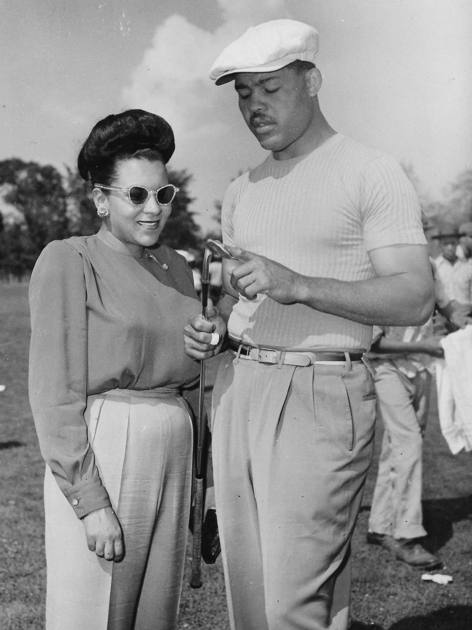 Boxing champion Joe Louis and his wife, Marva, look over his lucky No. 7 iron before he tees off in a Cleveland amateur competition Aug. 12, 1947, at Seneca Golf Course in Broadview Heights.