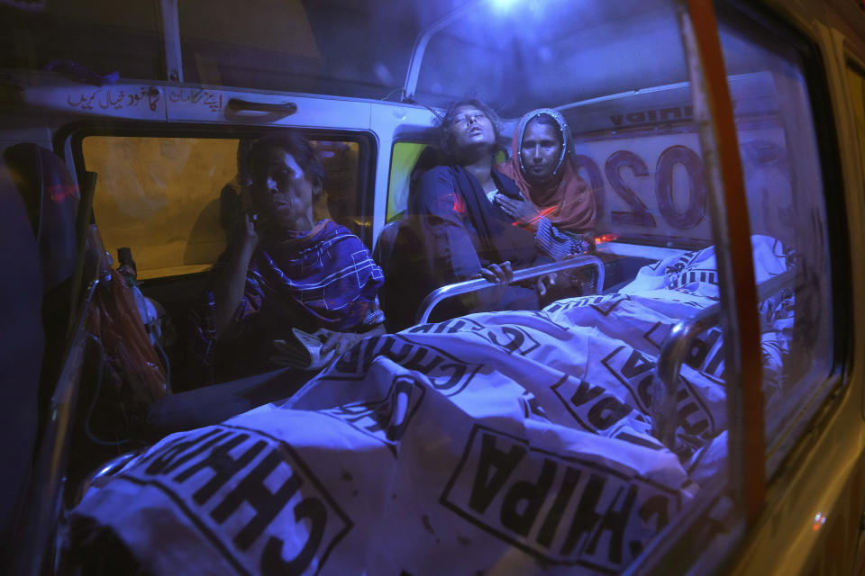 Relatives mourn next to the body of their family member, who died in a stampede, in an ambulance at a hospital, in Karachi, Pakistan, Friday, March 31, 2023. Several people were killed in the deadly stampede at a Ramadan food distribution center outside a factory in Pakistan's southern port city of Karachi, police and rescue officials said. (AP Photo/Fareed Khan)