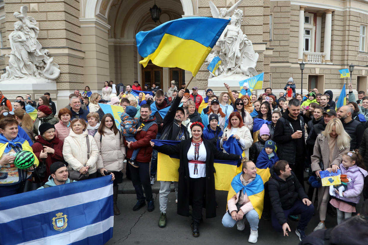 Residents of Kherson temporarily living in Odessa, holding Ukrainian flags, celebrate the liberation of their native town in front of The Odessa National Academic Opera and Ballet Theatre in Odessa, on November 12, 2022, amid Russia's invasion of Ukraine.