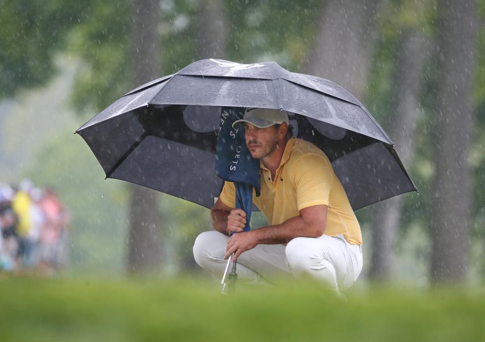 Brooks Koepka looks over his putt on the 9th green as the rains come down during the second round at the PGA Championship at Oak Hill Country Club Friday, May 19, 2023. 