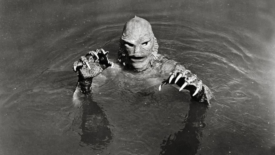 a gilled creature emerges from a lake in a scene from 'the creature from the black lagoon,' a good housekeeping pick for best halloween movies