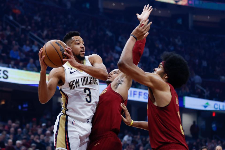 New Orleans Pelicans guard CJ McCollum (3) looks to pass the ball against Cleveland Cavaliers forward Isaac Okoro, center, and center Jarrett Allen, right, during the first half of an NBA basketball game, Monday, Jan. 16, 2023, in Cleveland. (AP Photo/Ron Schwane)