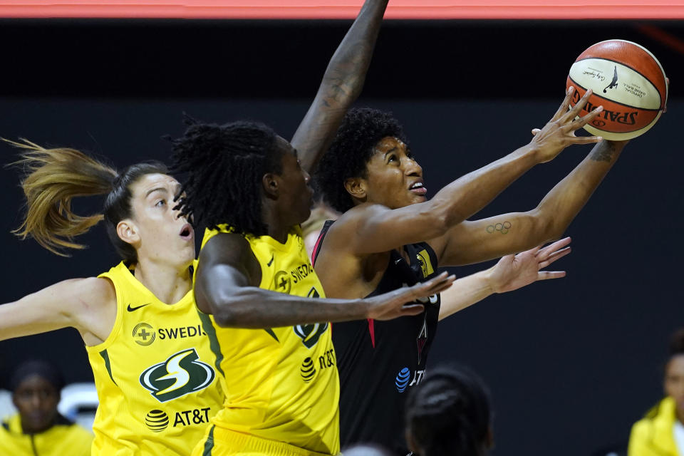 Las Vegas Aces forward Angel McCoughtry (35) drives to the basket after getting around Seattle Storm forward Breanna Stewart (30) and forward Natasha Howard (6) during the first half of Game 1 of basketball's WNBA Finals Friday, Oct. 2, 2020, in Bradenton, Fla. (AP Photo/Chris O'Meara)