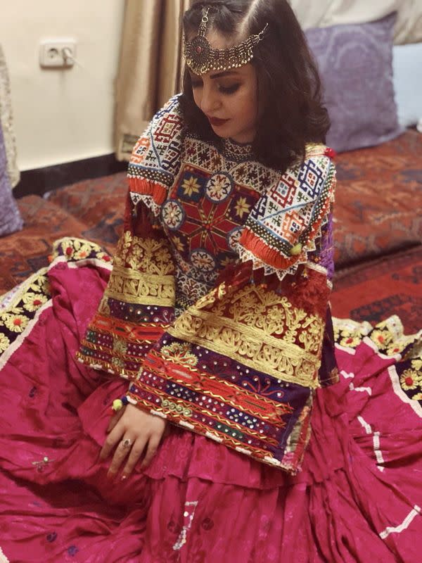 A woman poses in traditional Afghan attire, in Kabul