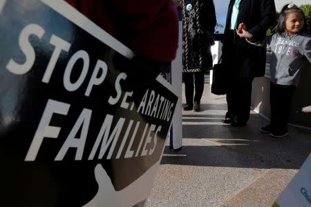 FILE PHOTO: Demonstrators holding an "Interfaith Prayer Vigil for Immigrant Justice" talk to ethnic Chinese Christians who fled Indonesia after wide scale rioting decades ago and overstayed their visas in the U.S., following their family meeting, including their five year-old daughter (C), with ICE, in Manchester, New Hampshire, U.S. on October 13, 2017. REUTERS/Brian Snyder/File Photo