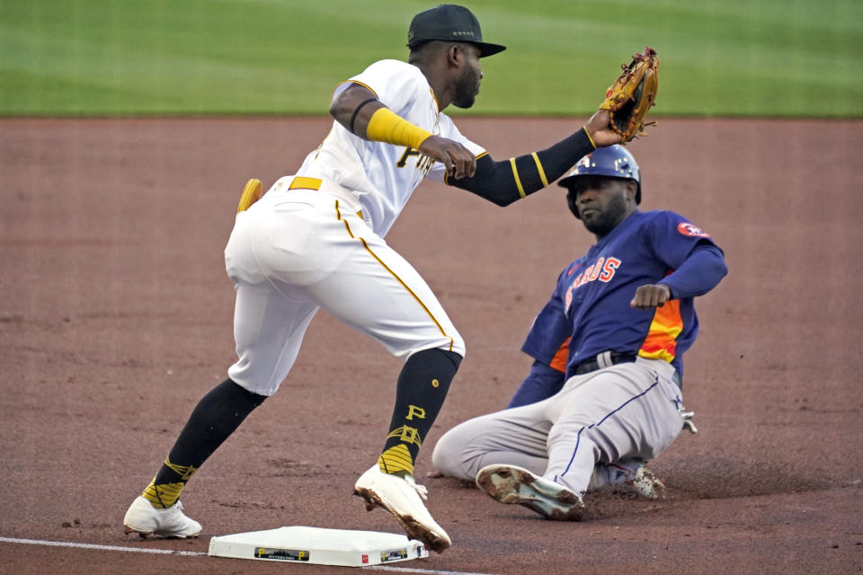 Pittsburgh Pirates shortstop, left, takes the throw at third base before tagging out Houston Astros' Yordan Alvarez, right, on the front end of a double steal during the first inning of a baseball game in Pittsburgh, Monday, April 10, 2023. (AP Photo/Gene J. Puskar)