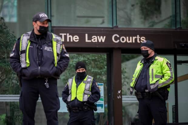 Vancouver police officers wait outside the downtown B.C. Supreme Court building where Meng Wanzhou's extradition proceedings are being held. 