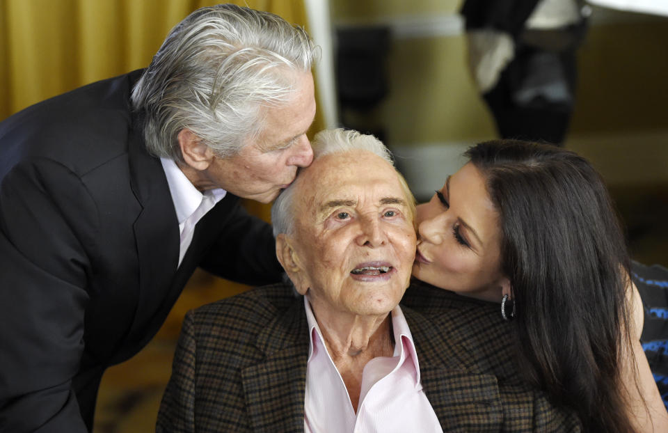 Actor Kirk Douglas, center, gets a kiss from his son Michael Douglas, left, and Michael's wife Catherine Zeta-Jones during his 100th birthday party at the Beverly Hills Hotel. Source: AAP