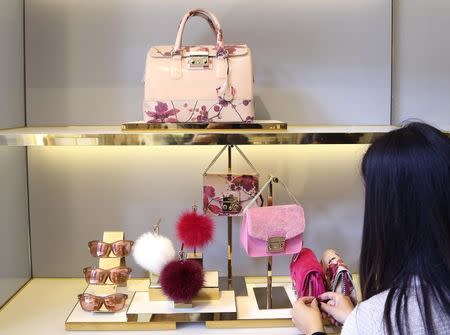 A shop assistant arranges bags in the window at the Furla flagship downtown Milan, September 17, 2014. REUTERS/Stefano Rellandini