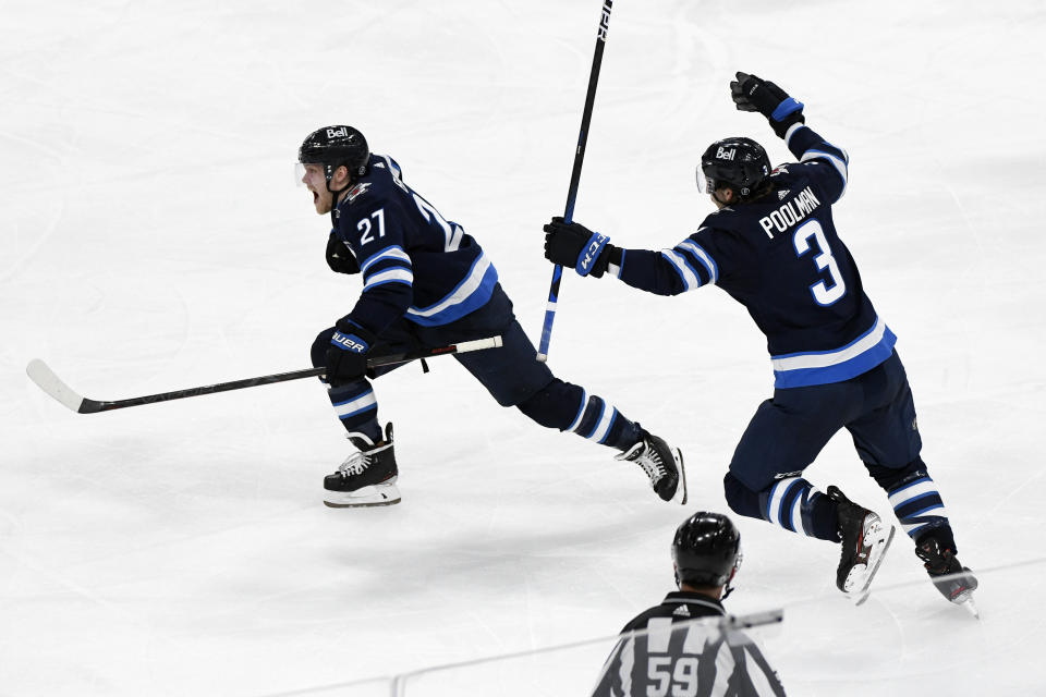 Winnipeg Jets' Nikolaj Ehlers (27) celebrates his game-winning goal with teammate Tucker Poolman (3) in the first overtime period of an NHL hockey Stanley Cup playoff game against the Edmonton Oilers, Sunday, May 23, 2021, in Winnipeg, Manitoba. (Fred Greenslade/The Canadian Press via AP)