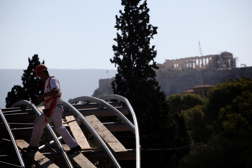 A worker walks on the roof top of a construction site for a new car parking area of a metro station as the ancient Parthenon temple is seen in the background, on Wednesday, Oct. 3, 2012. According to forecasts in the draft budget submitted to Greece's Parliament on Monday this year's recession will see the economy shrink around 6.5 percent, the document estimated. Unemployment is predicted to rise to 24.7 percent in 2013 from an average 23.5 percent in 2012.(AP Photo/Petros Giannakouris)