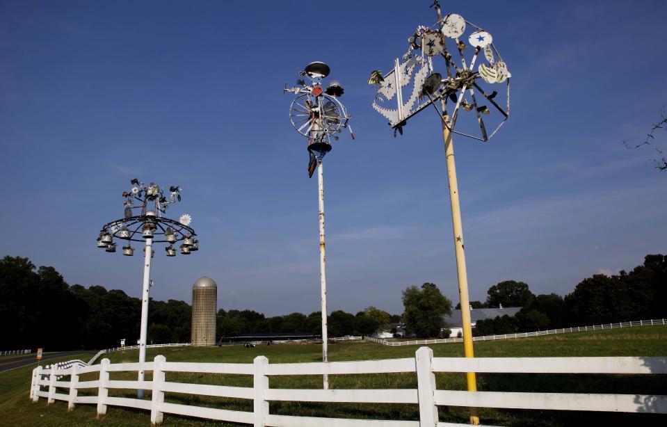 This Monday, June 25, 2012 file photo shows whirligigs by Vollis Simpson along the entrance to Fearrington Village near Pittsboro, N.C. Simpson, a self-taught artist famed for his whimsical, wind-powered whirligigs, has died. He was 94. Simpson's wife, Jean, told the Wilson Daily Times that her husband died in his sleep Friday, May 31, 2013. (AP Photo/Gerry Broome)