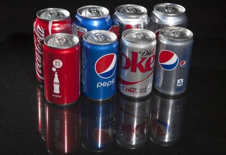 Regular and mini cans of Coke and Pepsi are pictured in this photo illustration in New York August 5, 2014. REUTERS/Carlo Allegri/Files