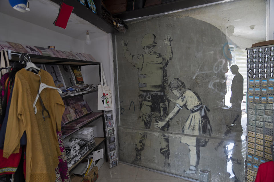 Un mural del reservado artista de grafiti británico Banksy está cubierto con vidrio protector dentro de una tienda de regalos, en la ciudad de Belén, Cisjordania, el jueves 4 de agosto de 2022. (Foto AP/Nasser Nasser)