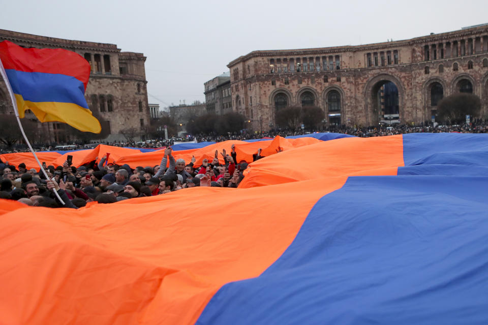 A crowd holds a huge Armenian national flag during a rally of supporters of Armenian Prime Minister Nikol Pashinyan in the center of Yerevan, Armenia, Monday, March 1, 2021. Amid escalating political tensions in Armenia, supporters of the country's embattled prime minister and the opposition are staging massive rival rallies in the capital of Yerevan. Prime Minister Nikol Pashinyan has faced opposition demands to resign since he signed a peace deal in November that ended six weeks of intense fighting with Azerbaijan over the Nagorno-Karabakh region. (PHOTOLURE via AP)