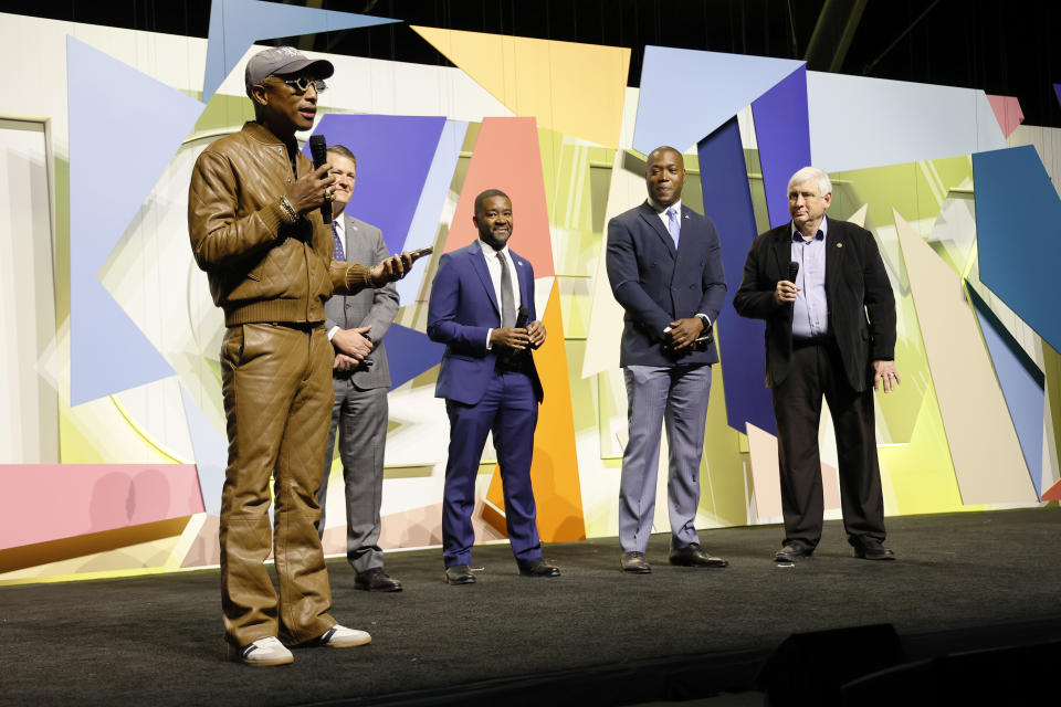 (L-R) Pharrell Williams, Deputy City Manager Taylor Adams, City Manager Patrick Duhaney, Council Member Aaron Rouse and Mayor Bobby Dyer speak onstage.