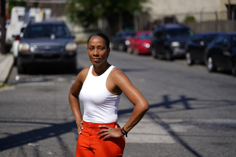 Kimberly Washington, executive director of the Frankford Community Development Corporation, and who has worked with community members to address abandoned cars, poses for a portrait on a street frequently used to discard cars in Philadelphia, Thursday, July 14, 2022. The abandoned cars bring “trash in the areas, then you know other crimes, quality of life issues, drug dealing, shootings, killings,” says Washington. “This starts to look like the place where this can all go down because no one cares.” (AP Photo/Matt Rourke)