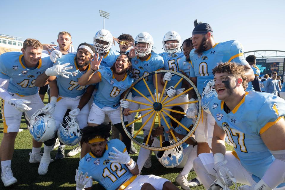 The Kent State Golden Flashes pose with the Wagon Wheel after defeating the University of Akron Zips 33-27 on Saturday at Dix Stadium.