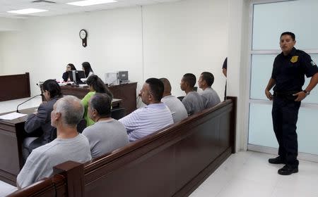 A police officer (R) stands guard as the six men accused of the kidnapping and killing of 11 women listen to the verdict at a court room in the Mexican border city of Ciudad Juarez, Mexico July 27, 2015. REUTERS/Jose Luis Gonzalez