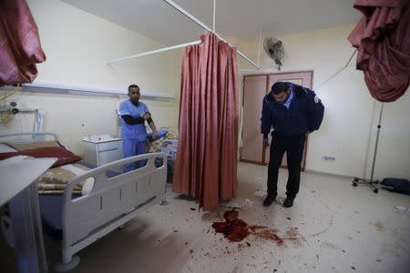 A medic looks at blood stain of a Palestinian man who was killed by Israeli undercover forces during a raid at Al-Ahly hospital in the West Bank city of Hebron November 12, 2015. REUTERS/Mussa Qawasma