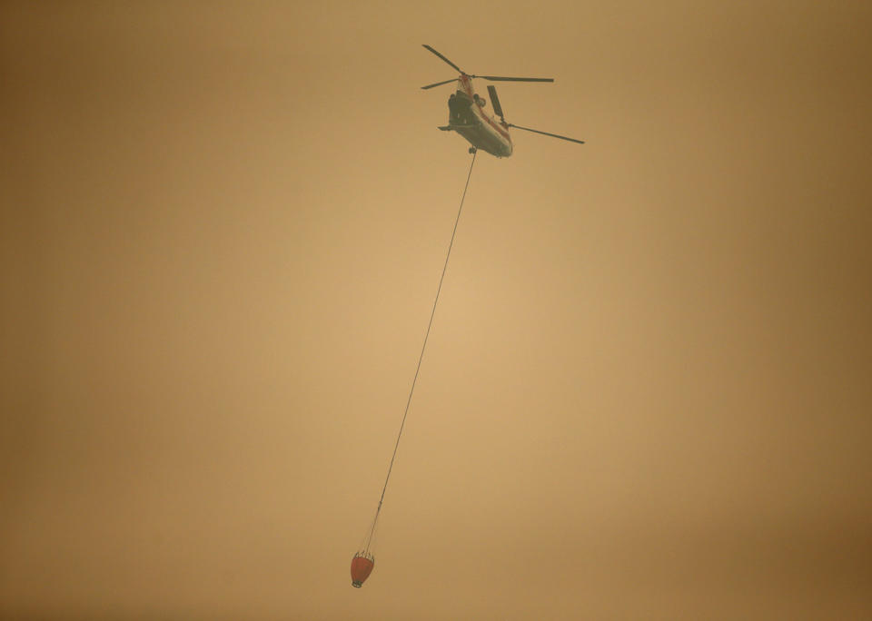 <p>A helicopter with a water bucket flies through dense smoke near Stevenson, Wash., on Sept. 6, 2017, as it works to battle the Eagle Creek wildfire on the Oregon side of the Columbia River Gorge. (Photo: Randy L. Rasmussen/AP) </p>