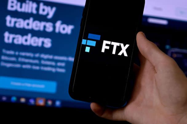 PHOTO: In this Feb. 10, 2022, file photo, a smart phone screen is displaying the logo of FTX, the crypto exchange platform, with a screen showing the FTX website in the background. (Olivier Douliery/AFP via Getty Images, FILE)