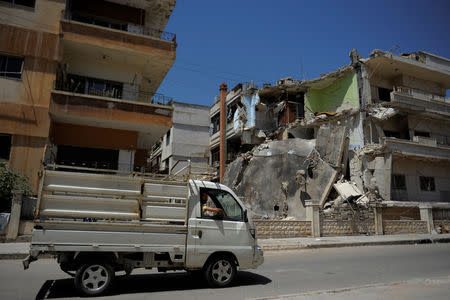 A truck passes a damaged building in Waer district in the central Syrian city of Homs, Syria July 26, 2017. Picture taken July 26, 2017. REUTERS/Omar Sanadiki