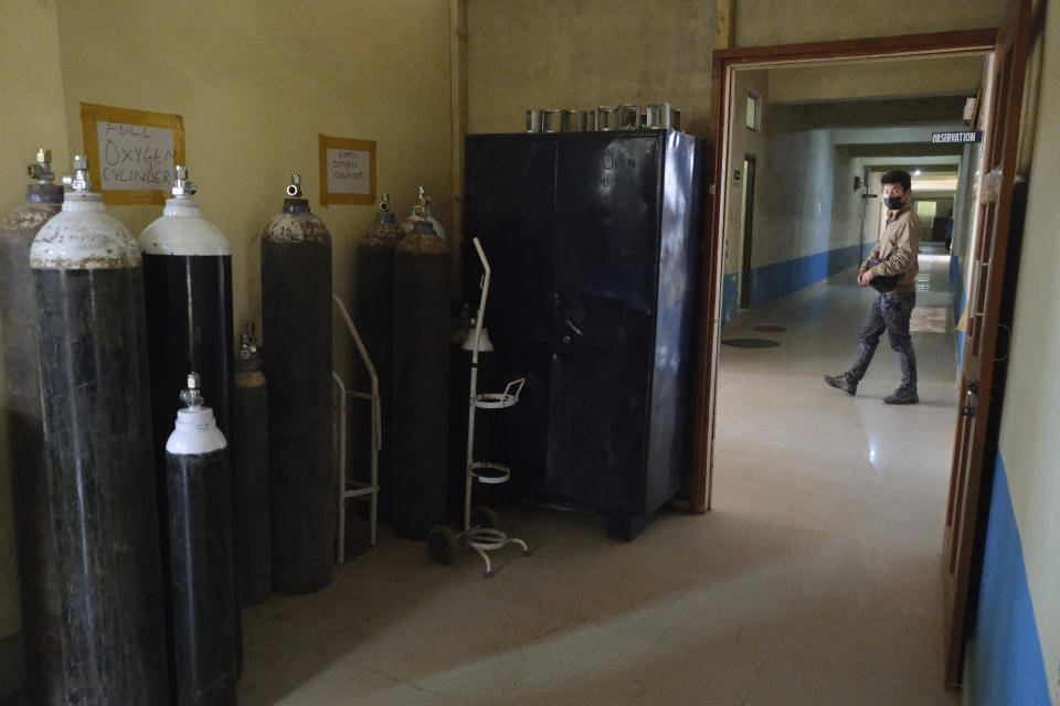 A man walks past a room where oxygen cylinders are stored at the District Hospital in Ukhrul, in the northeastern Indian state of Manipur, Friday, Jan. 15, 2021. This is the only government-run medical facility in the district that caters to a population of 180,000. The country's COVID-19 vaccination campaign that began Saturday is also being carried out here. (AP Photo/Yirmiyan Arthur)