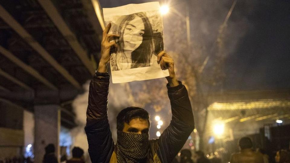 Un manifestante en Irán con la imagen del rostro de una mujer.