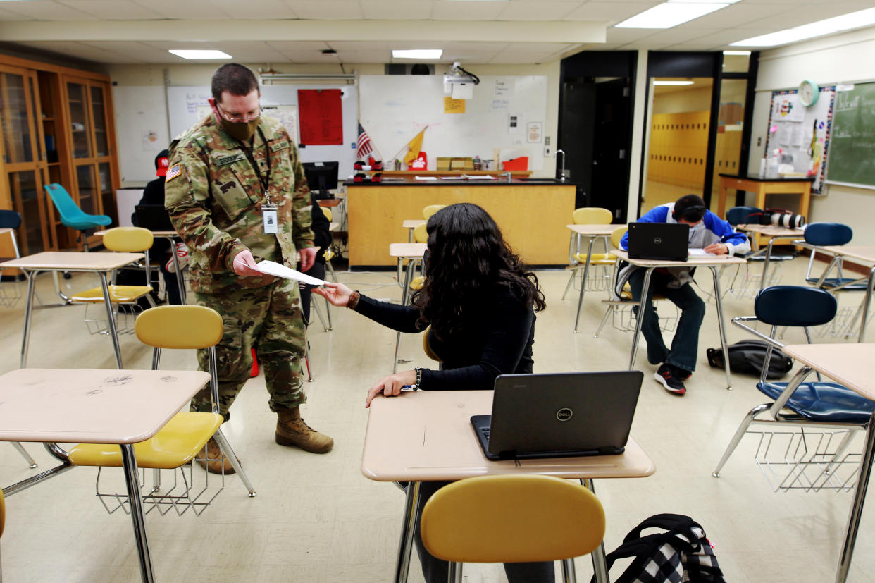 Substitute teacher and New Mexico Army National Guard specialist Michael Stockwell takes a geology assignment from Lilli Terrazas, 15, at Alamogordo High School. (AP)