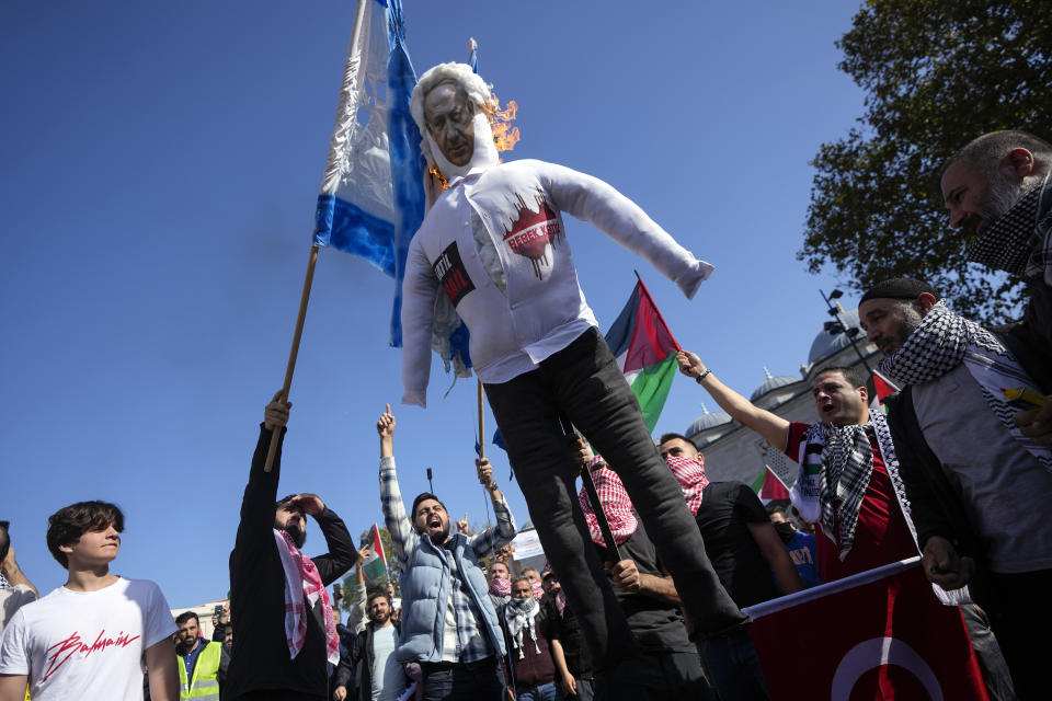 Protesters chant slogans while burning a doll with a picture of Israeli Prime Minister Benjamin Netanyahu, and a mock of an Israeli flag during a protest to show their solidarity with the Palestinians, in Istanbul, Turkey. Friday, Oct. 20, 2023. (AP Photo/Khalil Hamra)