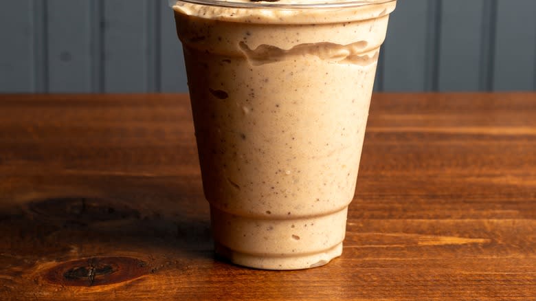 Brown milkshake on counter with straw