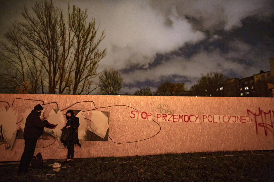 Protesters stand by a fence after writing "Stop Police Violence" on it in Warsaw, Poland, Thursday, Nov. 19, 2020. (AP Photo/Agata Grzybowska)